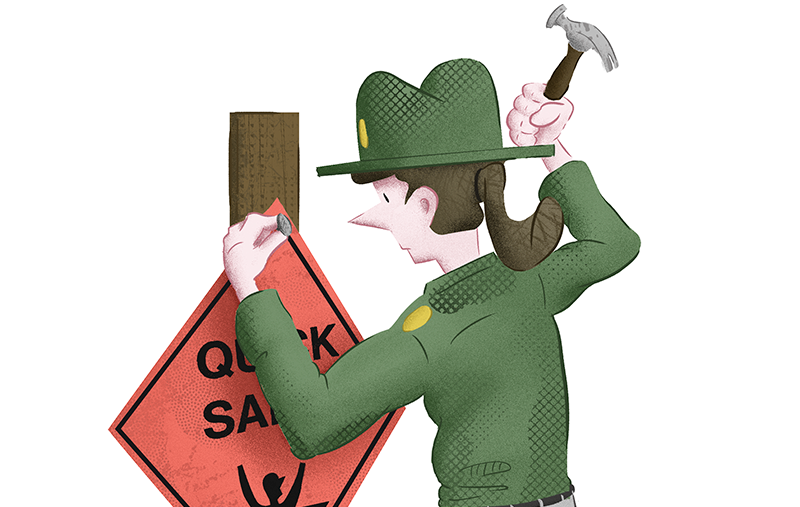 Female park ranger nailing an orange quicksand sign to a post